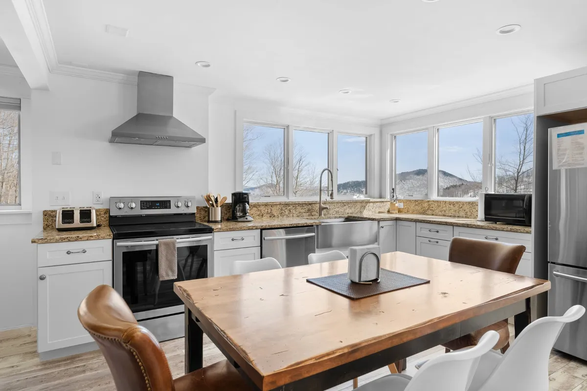 A cozy, inviting kitchen with a spacious island, granite countertops, large windows that frame scenic mountain views, and stainless steel appliances. The space is filled with natural light, making it ideal for morning coffee, meal prep, or family gatherings.