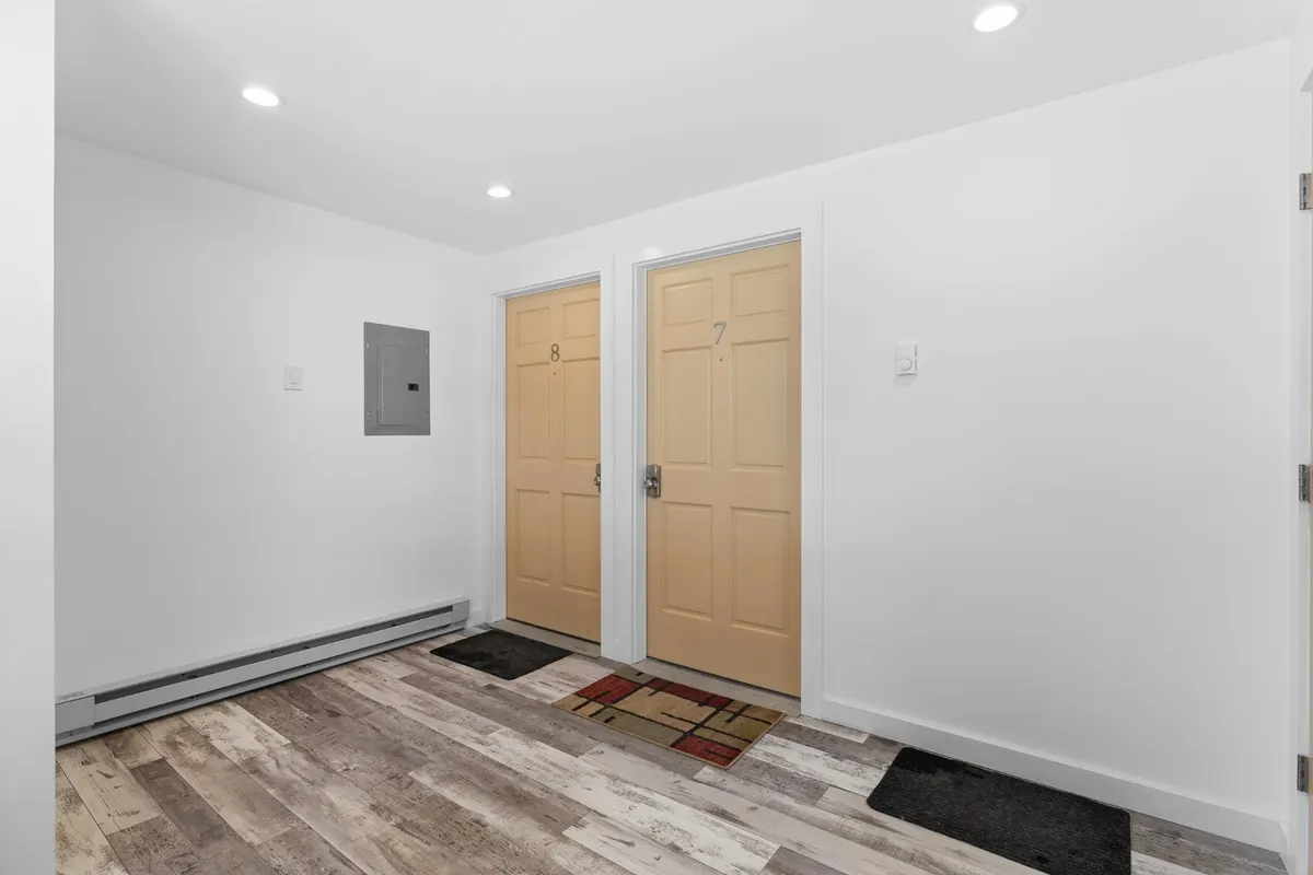 An inviting entryway scene featuring doors numbered 7 and 8, stylish doormats, and modern lighting fixtures. The space is functional and welcoming, capturing the first impression upon entering the property and highlighting accessibility.